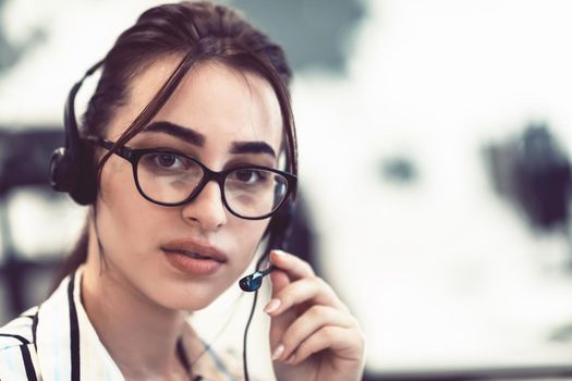 Business and technology concept - helpline female operator with headphones in a call center.Businesswoman with headsets working in a call center. High-quality photo