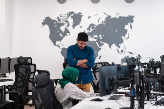 Multiethnic startup business team Arabian woman wearing a hijab on meeting in modern open plan office interior brainstorming, working on laptop and desktop computer. Selective focus. High-quality photo