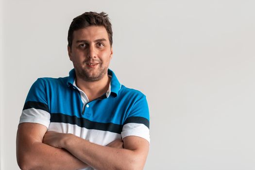 Formal business male portrait. A confident successful casual businessman or manager stands in front of a white background, arms crossed, looking directly at the camera and smiling friendly. High-quality photography.