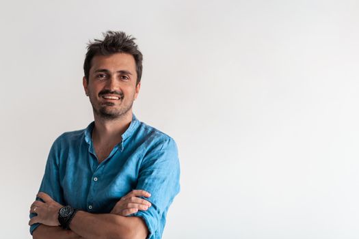 Formal business male portrait. A confident successful casual businessman or manager stands in front of a white background, arms crossed, looking directly at the camera and smiling friendly. High-quality photography.