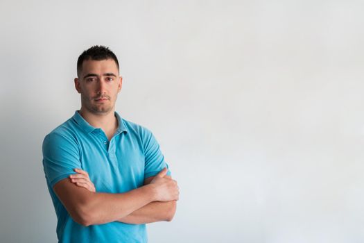 Formal business male portrait. A confident successful casual businessman or manager stands in front of a white background, arms crossed, looking directly at the camera and smiling friendly. High-quality photography.