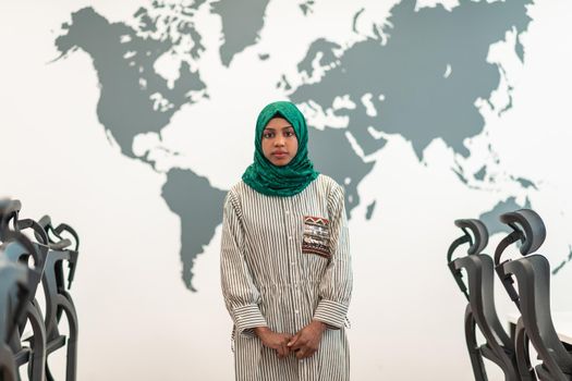 Portrait of Muslim female software developer with green hijab standing at modern open plan startup office. High-quality photo