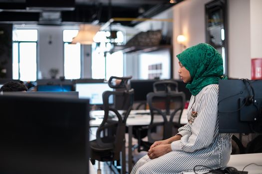 Arabian woman wearing a hijab on meeting in modern open plan office interior brainstorming, working on laptop and desktop computer. Selective focus. High-quality photo