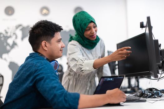 Multiethnic startup business team Arabian woman wearing a hijab on meeting in modern open plan office interior brainstorming, working on laptop and desktop computer. Selective focus. High-quality photo