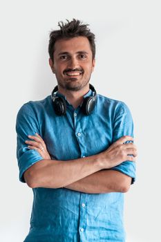 Formal business male portrait. A confident successful casual businessman or manager stands in front of a white background, arms crossed, looking directly at the camera and smiling friendly. High-quality photography.