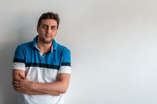 Formal business male portrait. A confident successful casual businessman or manager stands in front of a white background, arms crossed, looking directly at the camera and smiling friendly. High-quality photography.