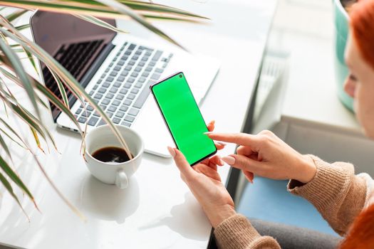 Young woman working,scrolling and checking her phone. Focus on the mobile phonechromakey, green screen on screen.