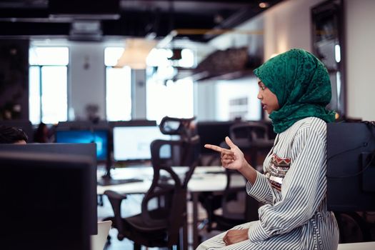 Multiethnic startup business team Arabian woman wearing a hijab on meeting in modern open plan office interior brainstorming, working on laptop and desktop computer. Selective focus. High-quality photo