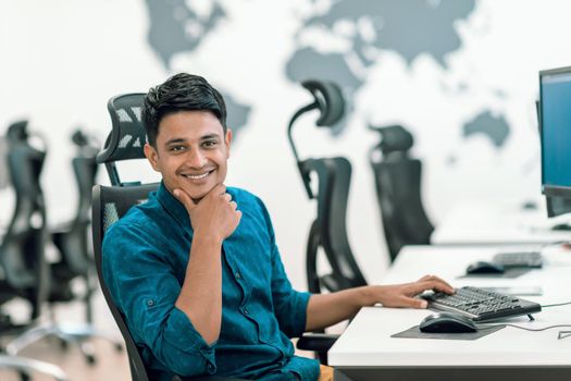 Casual businessman working on a desktop computer in modern open plan startup office interior. Selective focus. High-quality photo