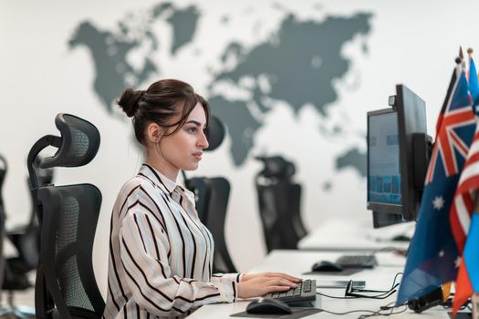 Casual businesswoman working on a desktop computer in modern open plan startup office interior. Selective focus. High-quality photo