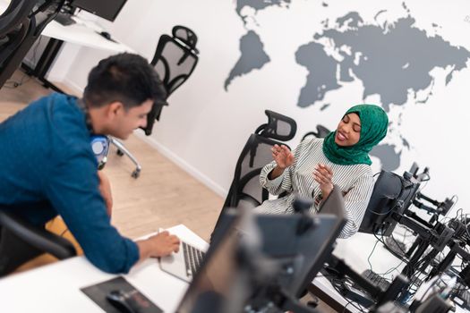 Multiethnic startup business team Arabian woman wearing a hijab on meeting in modern open plan office interior brainstorming, working on laptop and desktop computer. Selective focus. High-quality photo