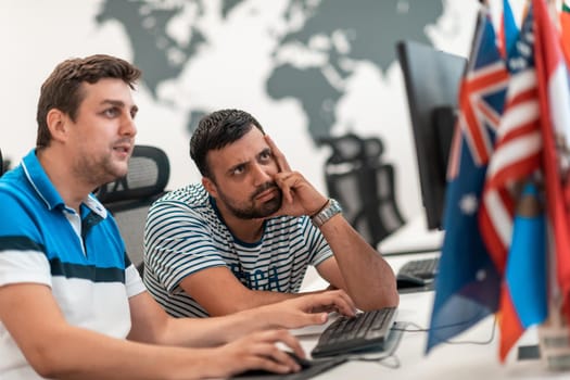 Group of Casual businessmen working on a desktop computer in modern open plan startup office interior. Selective focus. High-quality photo