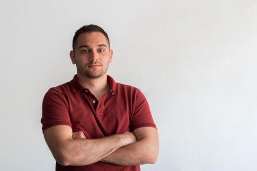 Formal business male portrait. A confident successful casual businessman or manager stands in front of a white background, arms crossed, looking directly at the camera and smiling friendly. High-quality photography.