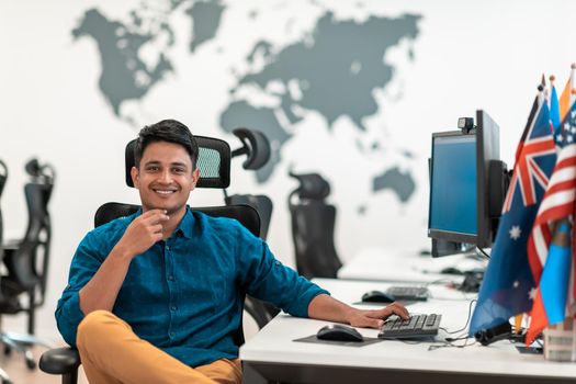 Casual businessman working on a desktop computer in modern open plan startup office interior. Selective focus. High-quality photo