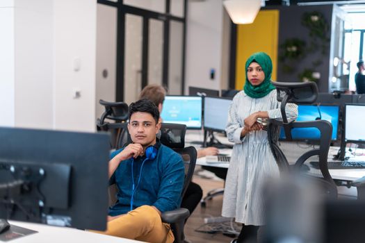 Multiethnic startup business team Arabian woman wearing a hijab on meeting in modern open plan office interior brainstorming, working on laptop and desktop computer. Selective focus. High-quality photo