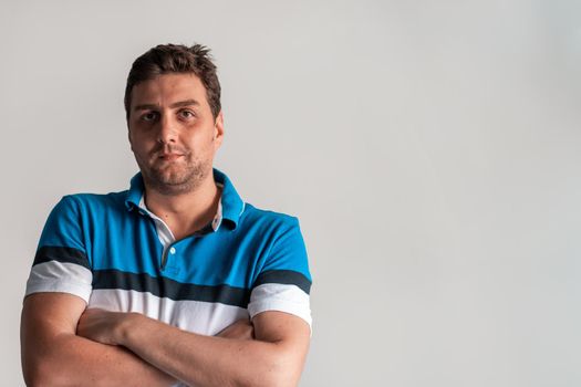 Formal business male portrait. A confident successful casual businessman or manager stands in front of a white background, arms crossed, looking directly at the camera and smiling friendly. High-quality photography.