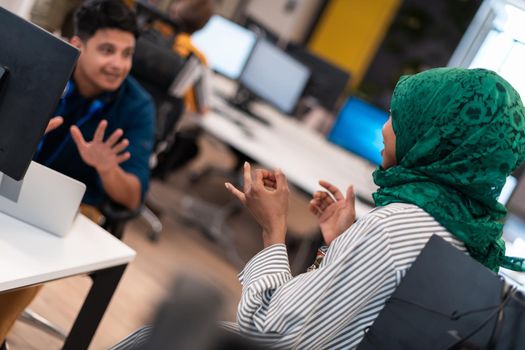 Multiethnic startup business team Arabian woman wearing a hijab on meeting in modern open plan office interior brainstorming, working on laptop and desktop computer. Selective focus. High-quality photo