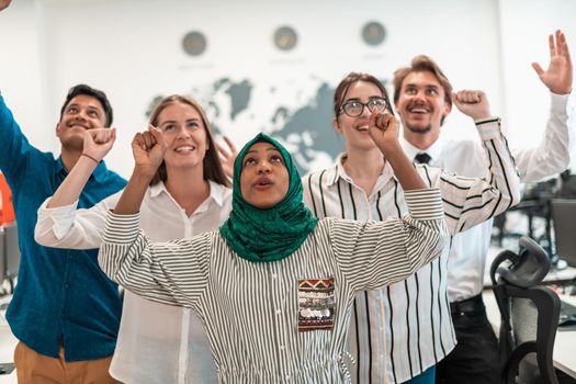 Portrait of young excited multiethnics business team of software developers standing and looking at the camera at modern startup office. High-quality photo