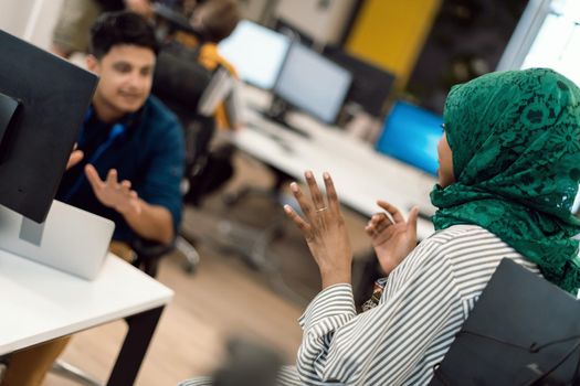 Multiethnic startup business team Arabian woman wearing a hijab on meeting in modern open plan office interior brainstorming, working on laptop and desktop computer. Selective focus. High-quality photo