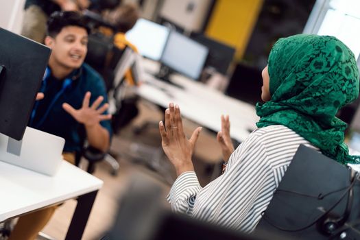 Multiethnic startup business team Arabian woman wearing a hijab on meeting in modern open plan office interior brainstorming, working on laptop and desktop computer. Selective focus. High-quality photo