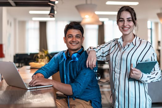 Multiethnic business people man with a female colleague working together on tablet and laptop computer in relaxation area of modern startup office. High-quality photo