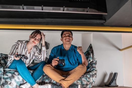 Work hard play hard. Workers Playing computer games man against a woman during break-in relaxation area at creative startup Office. High-quality photo