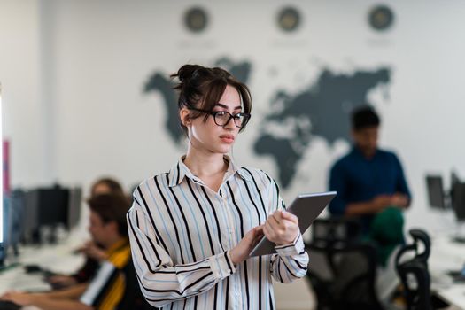 Portrait of businesswoman in casual clothes holding tablet computer at modern startup open plan office interior. Selective focus. High-quality photo