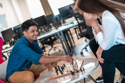 Multiethnic group of businesspeople playing chess while having a break in relaxation area at modern startup office. High-quality photo