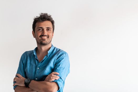 Formal business male portrait. A confident successful casual businessman or manager stands in front of a white background, arms crossed, looking directly at the camera and smiling friendly. High-quality photography.