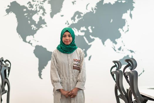 Portrait of Muslim female software developer with green hijab standing at modern open plan startup office. High-quality photo