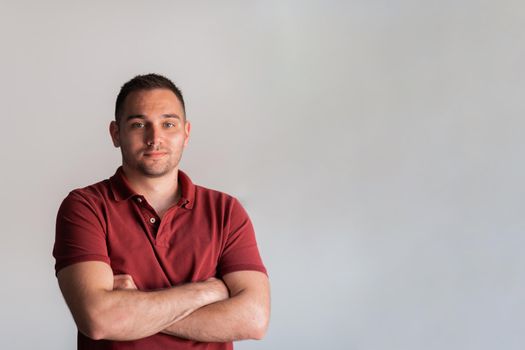 Formal business male portrait. A confident successful casual businessman or manager stands in front of a white background, arms crossed, looking directly at the camera and smiling friendly. High-quality photography.