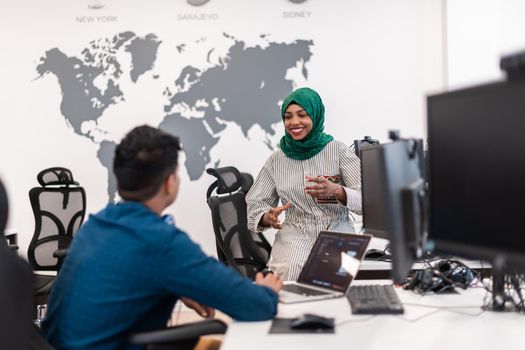 Multiethnic startup business team Arabian woman wearing a hijab on meeting in modern open plan office interior brainstorming, working on laptop and desktop computer. Selective focus. High-quality photo