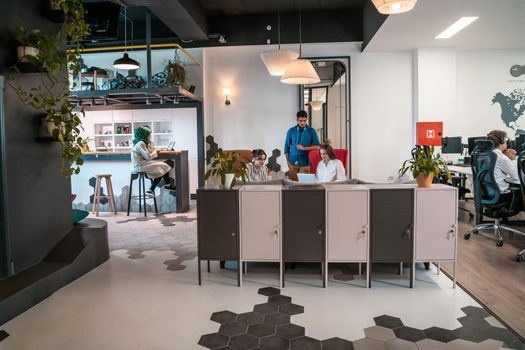 group of casual multiethnic business people taking break from the work doing different things while enjoying free time in relaxation area at modern open plan startup office. High quality photo