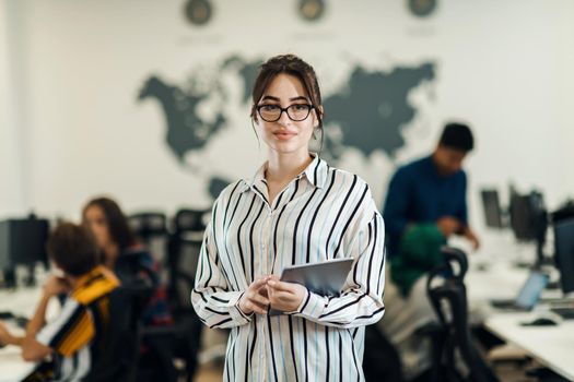 Portrait of businesswoman in casual clothes holding tablet computer at modern startup open plan office interior. Selective focus. High-quality photo