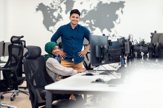 Multiethnic startup business team woman wearing a hijab on meeting in modern open plan office interior brainstorming, working on laptop and desktop computer. Selective focus. High-quality photo