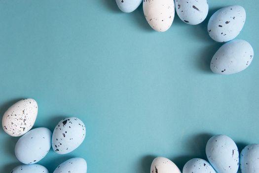 Easter background. Blue and white painted quail eggs on a blue background. Happy Easter holiday.