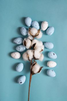Easter background. Blue and white painted quail eggs on a blue background, decorated with cotton. Happy Easter holiday.