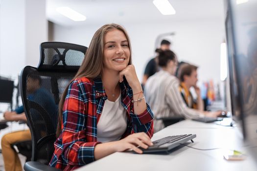 Casual businesswoman working on a desktop computer in modern open plan startup office interior. Selective focus. High-quality photo