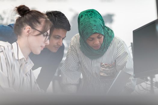 Multiethnic startup business team Arabian woman wearing a hijab on meeting in modern open plan office interior brainstorming, working on laptop and desktop computer. Selective focus. High-quality photo