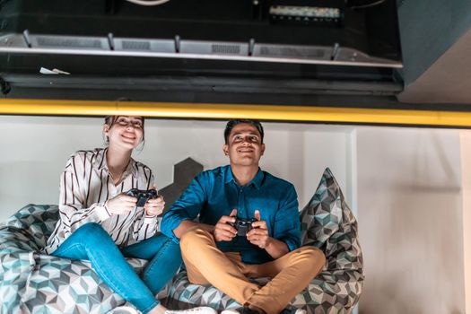 Work hard play hard. Workers Playing computer games man against a woman during break-in relaxation area at creative startup Office. High-quality photo