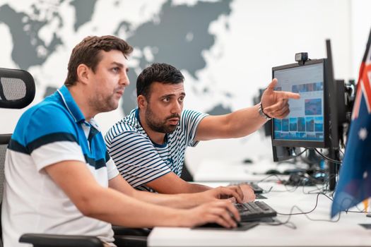 Group of Casual businessmen working on a desktop computer in modern open plan startup office interior. Selective focus. High-quality photo