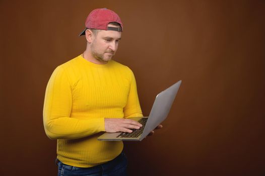 A man uses a laptop in the studio. Chubby man with his laptop stands in the studio.