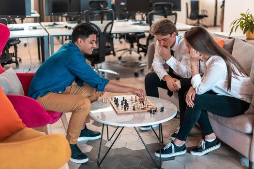 Multiethnic group of businesspeople playing chess while having a break in relaxation area at modern startup office. High-quality photo