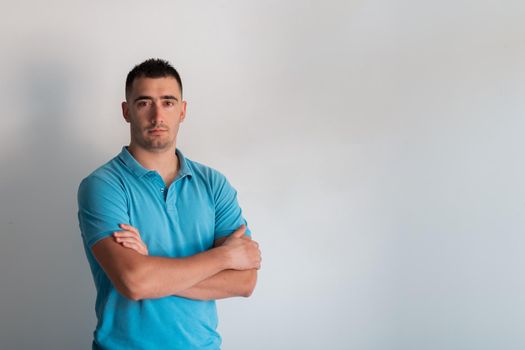 Formal business male portrait. A confident successful casual businessman or manager stands in front of a white background, arms crossed, looking directly at the camera and smiling friendly. High-quality photography.