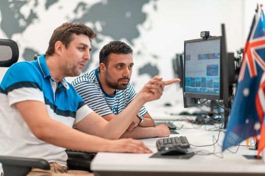 Group of Casual businessmen working on a desktop computer in modern open plan startup office interior. Selective focus. High-quality photo