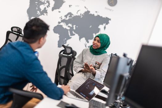 Multiethnic startup business team Arabian woman wearing a hijab on meeting in modern open plan office interior brainstorming, working on laptop and desktop computer. Selective focus. High-quality photo