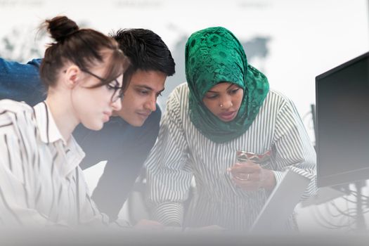 Multiethnic startup business team Arabian woman wearing a hijab on meeting in modern open plan office interior brainstorming, working on laptop and desktop computer. Selective focus. High-quality photo