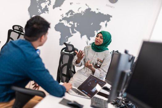 Multiethnic startup business team Arabian woman wearing a hijab on meeting in modern open plan office interior brainstorming, working on laptop and desktop computer. Selective focus. High-quality photo