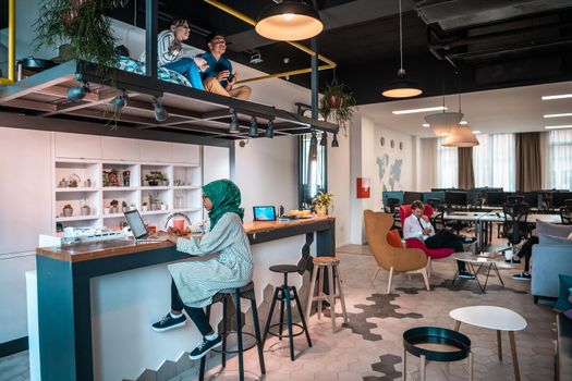 Group of casual multiethnic businesspeople taking a break from the work doing different things while enjoying free time in relaxation area at modern open plan startup office. High-quality photo