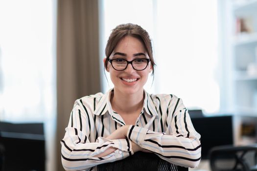 Portrait of businesswoman in casual clothes with glasses at modern startup open plan office interior. Selective focus. High-quality photo